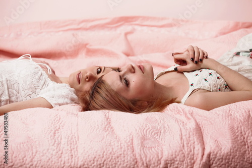Two young women lying on a pink blanket