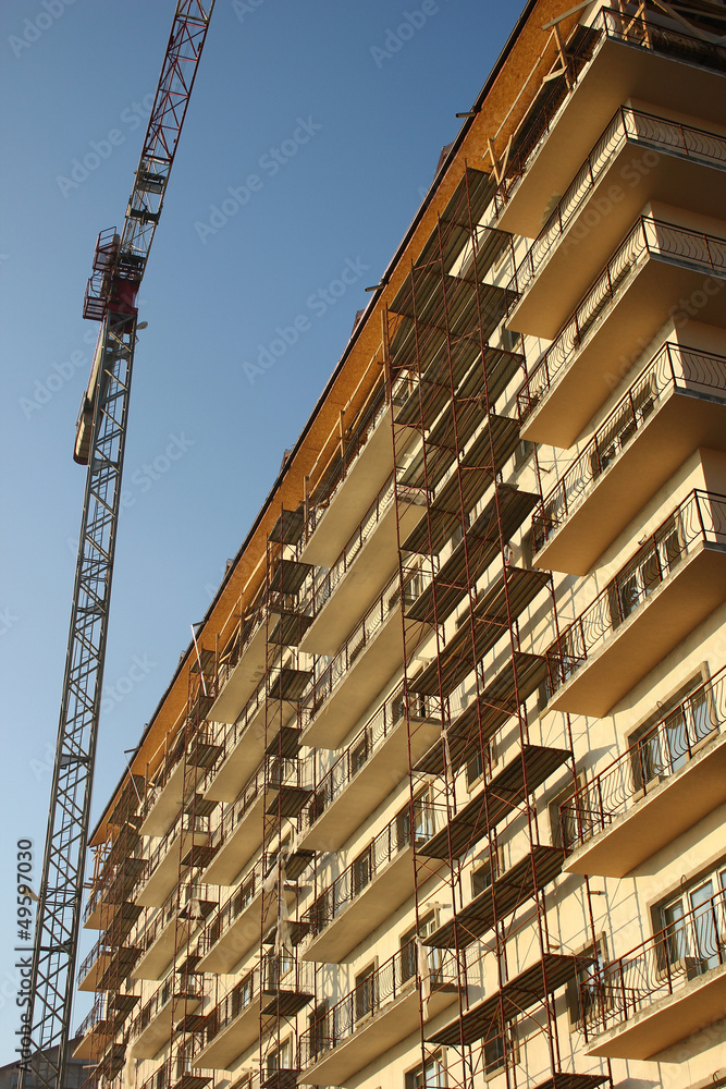 Crane next to building covered by scaffolds