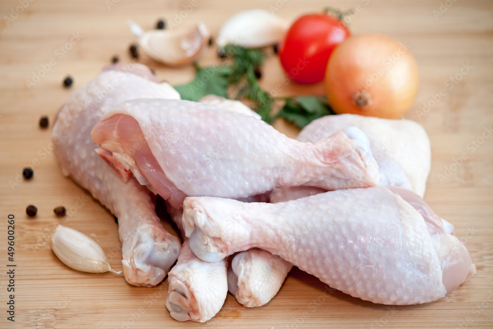 Raw chicken legs with vegetables and spices on the chopping boar Raw chicken legs with vegetables and spices on the chopping boar