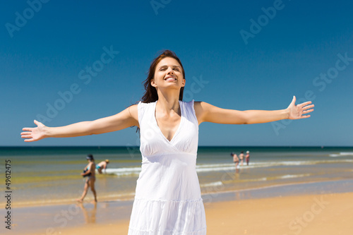 Attractive woman standing in the sun on beach photo