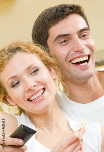 Cheerful young couple watching TV together