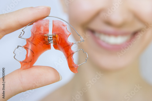 Smiling girl holding braces for teeth