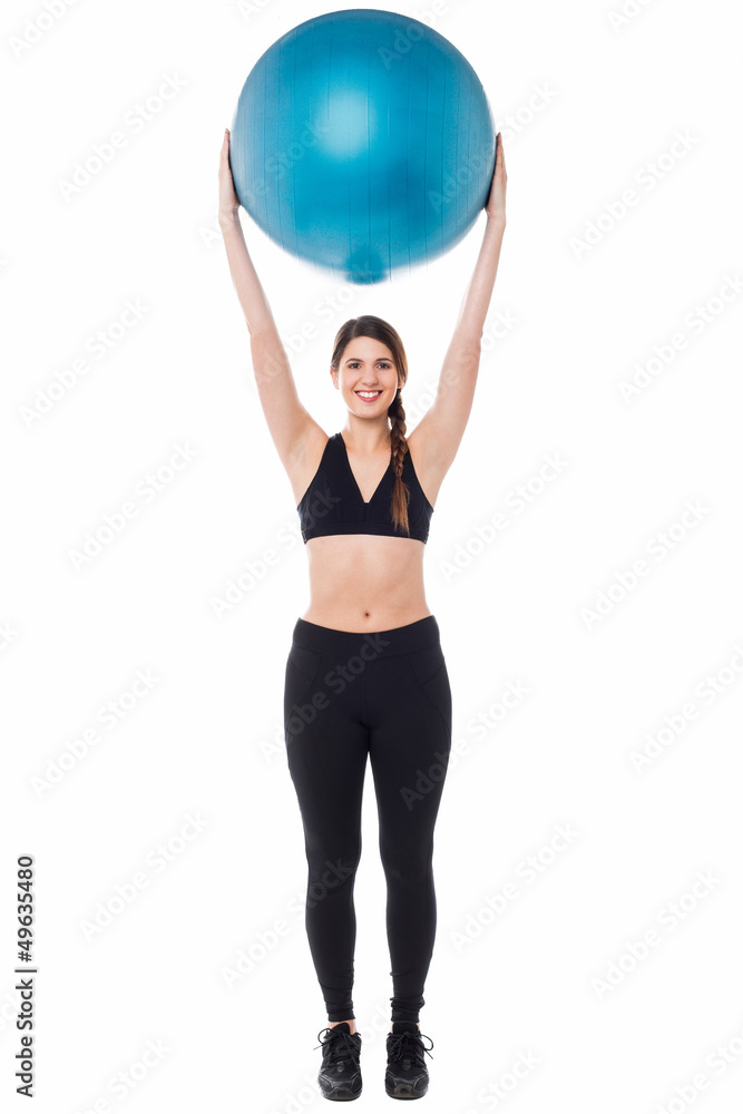 Fitness enthusiast holding ball above her head Fitness enthusiast holding ball above her head