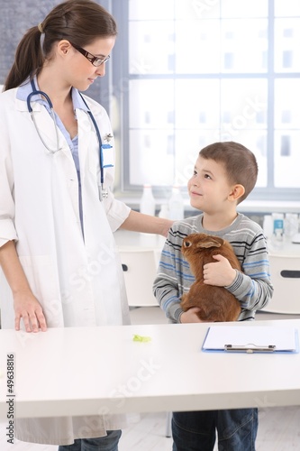 Vet and smiling kid with pet rabbit