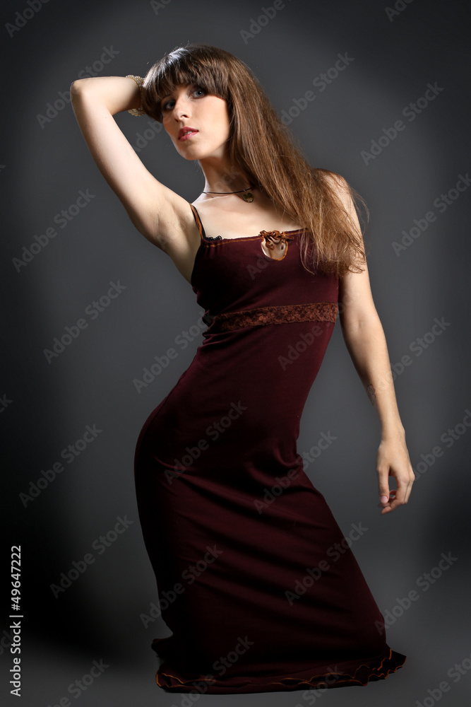Fototapeta premium young brunette in a red dress on a gray background