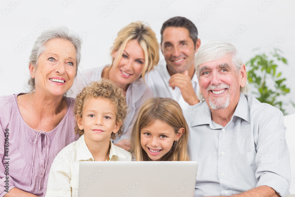 Family smiling in front of a laptop screen Family smiling in front of a laptop screen