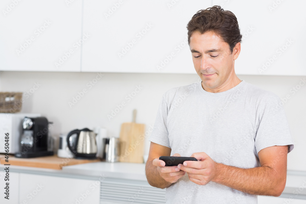 Man texting in the kitchen Man texting in the kitchen