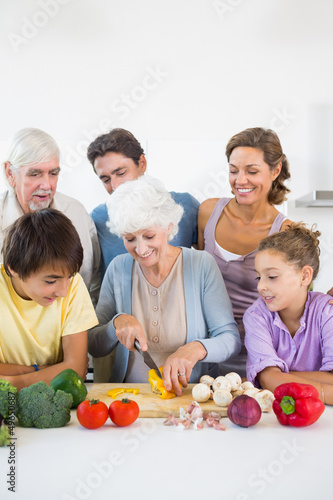 Family watching grandmother slicing pepper
