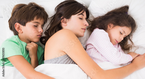 Mother sleeping with son and daughter