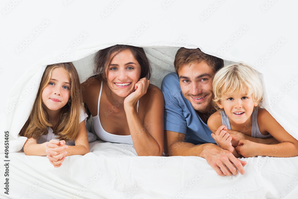 Happy family in the duvet smiling Happy family in the duvet smiling