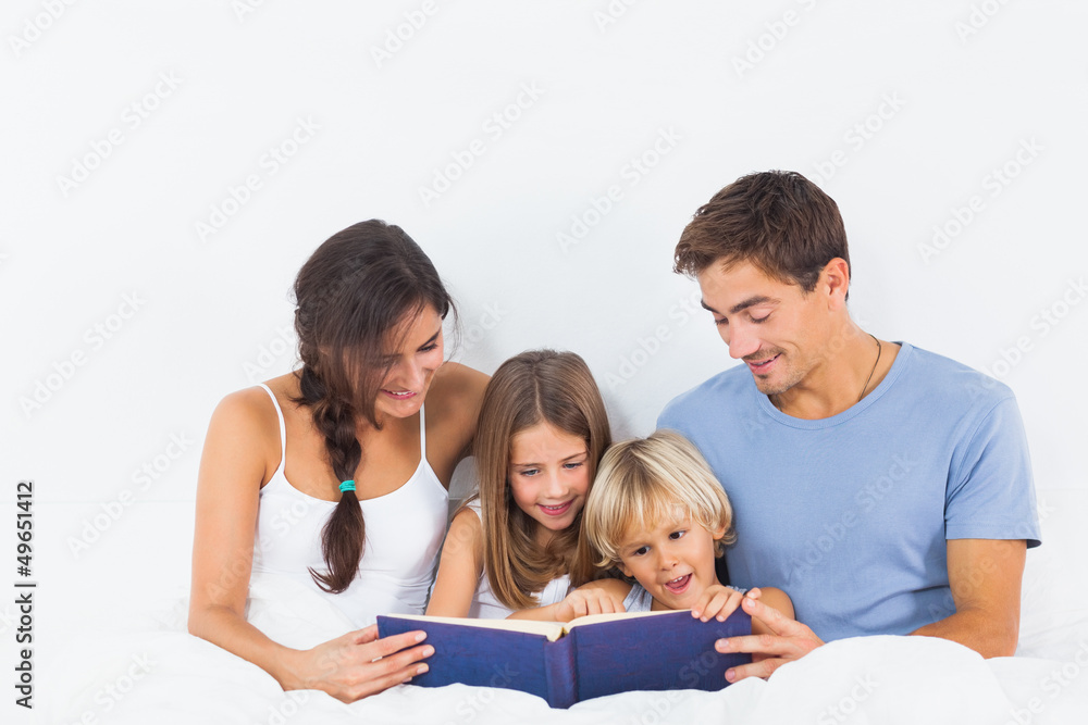Family sitting with a storybook on the bed Family sitting with a storybook on the bed