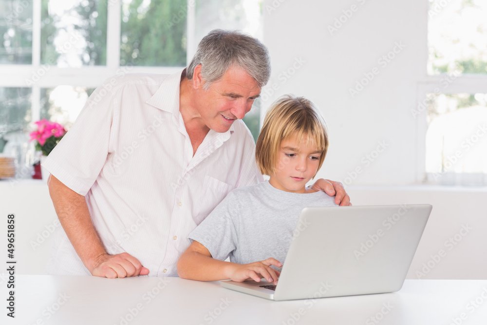 Grandfather and child looking at laptop with smile Grandfather and child looking at laptop with smile