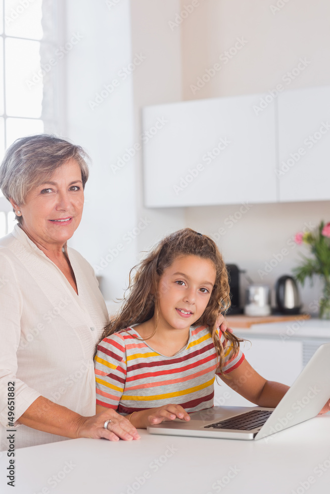 Smiling grandmother and child looking at the camera with laptop Smiling grandmother and child looking at the camera with laptop