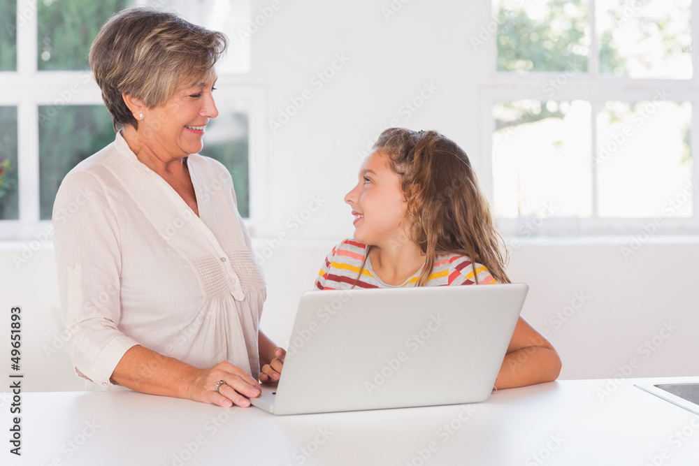 Smiling child and granny gazing with laptop Smiling child and granny gazing with laptop