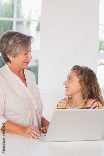 Smiling grandmother and child gazing with laptop