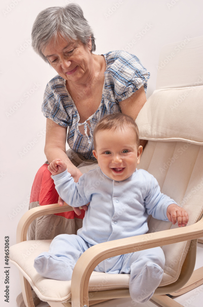 Baby sitting on chair and laughing with grandmother Baby sitting on chair and laughing with grandmother
