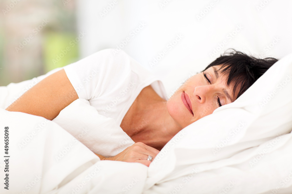 cute mature woman sleeping on bed - obrazy, fototapety, plakaty 