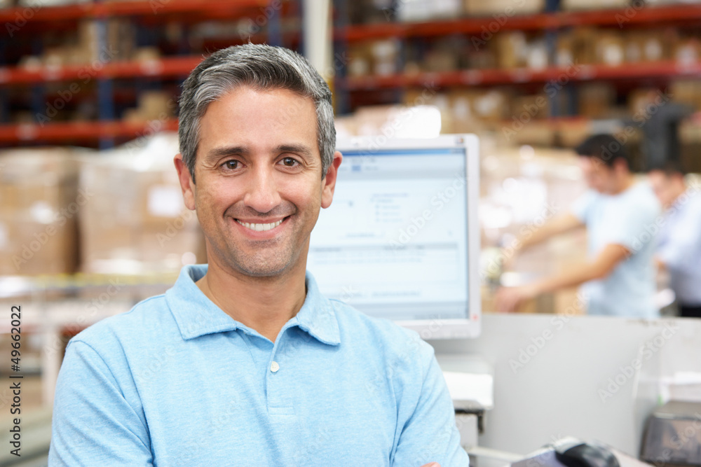 Obraz premium Man At Computer Terminal In Distribution Warehouse