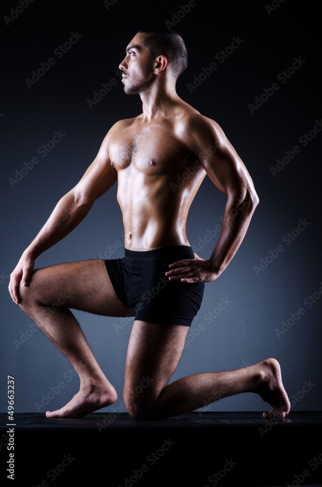 Muscular man in dark studio Muscular man in dark studio