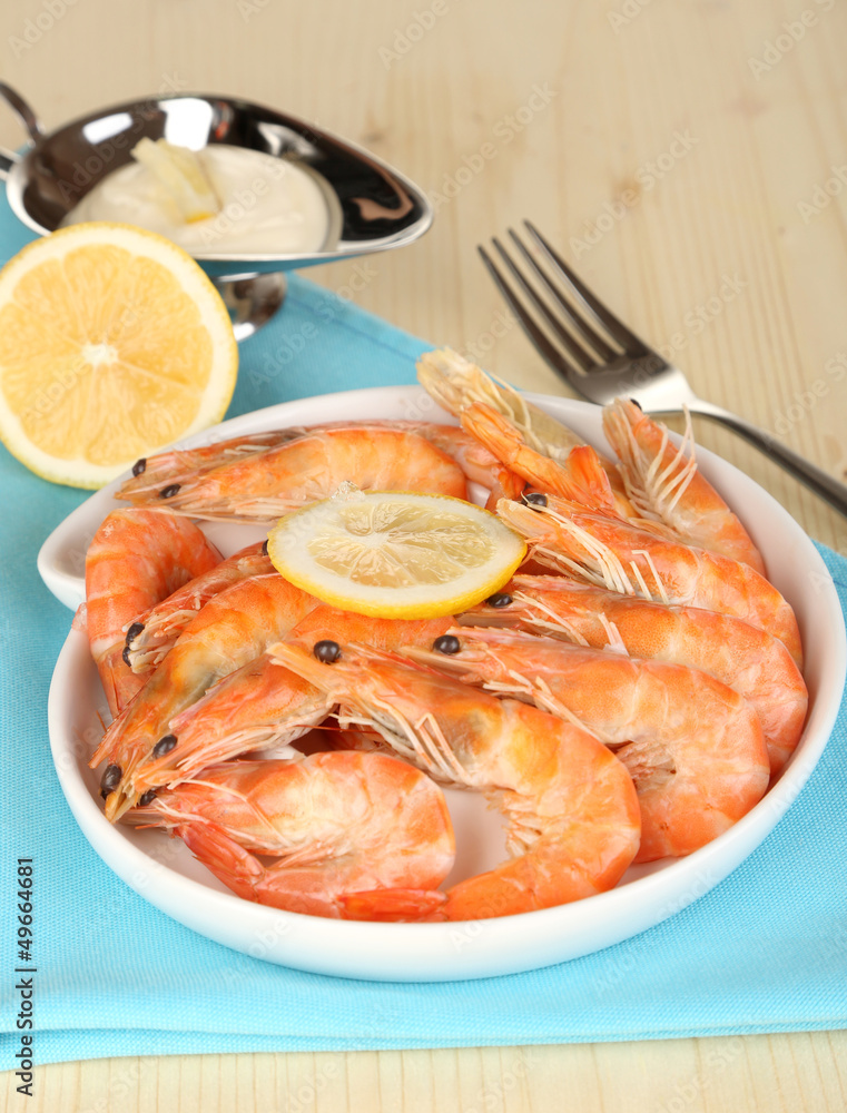 Shrimps with lemon on plate on wooden table close-up Shrimps with lemon on plate on wooden table close-up