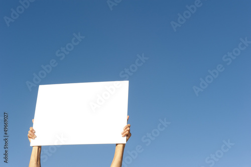 фотографія Hands holding blank billboard blue background