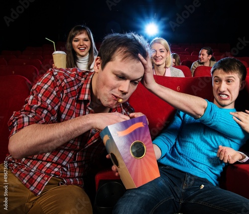 Impudent young man steal popcorn in cinema