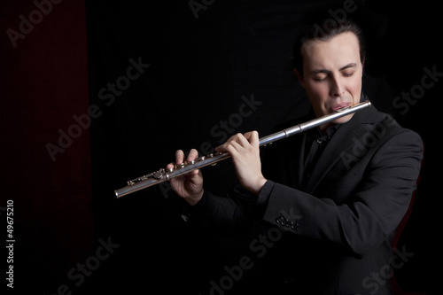 professional flutist musician playing flute on black background
