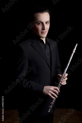 professional flutist musician playing flute on black background