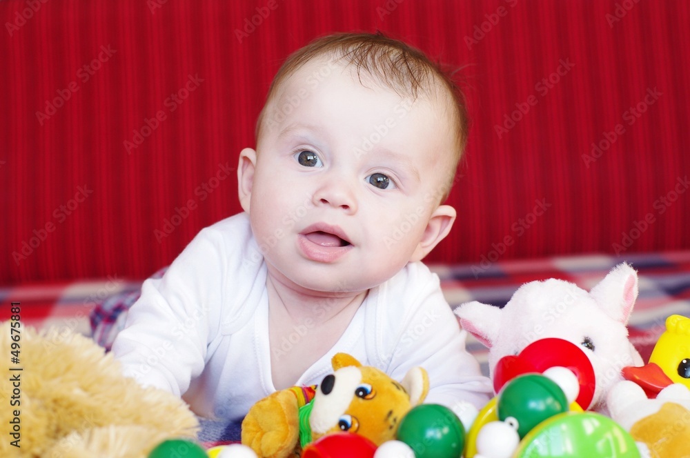 The baby lies on a sofa among toys The baby lies on a sofa among toys