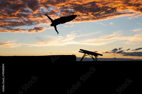 silhouette of gymnast on trampoline in sunset
