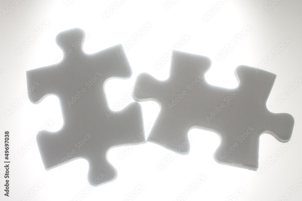 Connecting two puzzle pieces against the light. Connecting two puzzle pieces against the light.