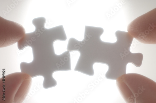 A person connecting puzzle pieces against the light.