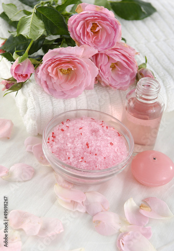Spa setting with pink rose with towel ,salt in bowl, massage oil