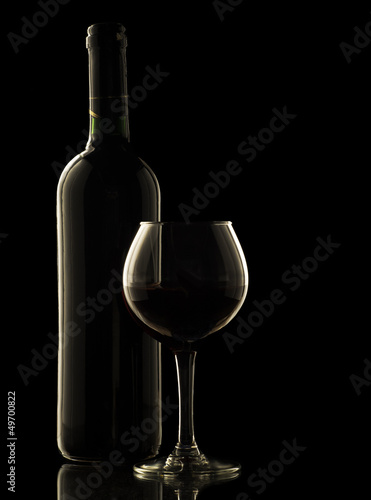 Red wine bottle and glass on black background