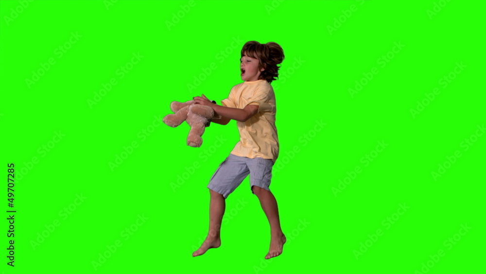 Young boy jumping up and catching teddy bear on green screen Young boy jumping up and catching teddy bear on green screen