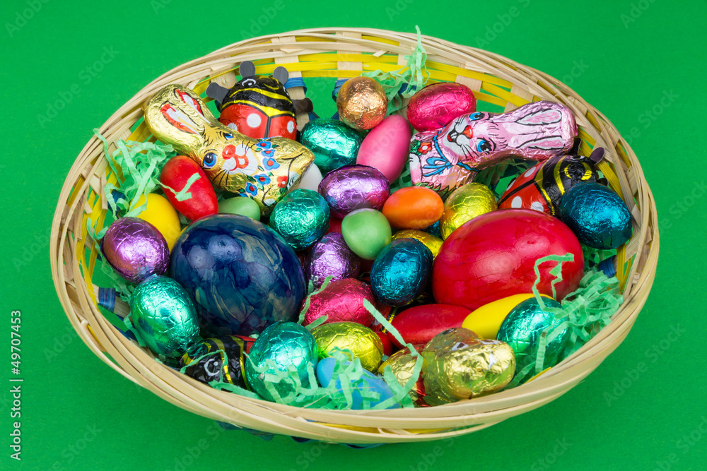 Obraz premium bunter Osterkorb mit Süßes auf grün
