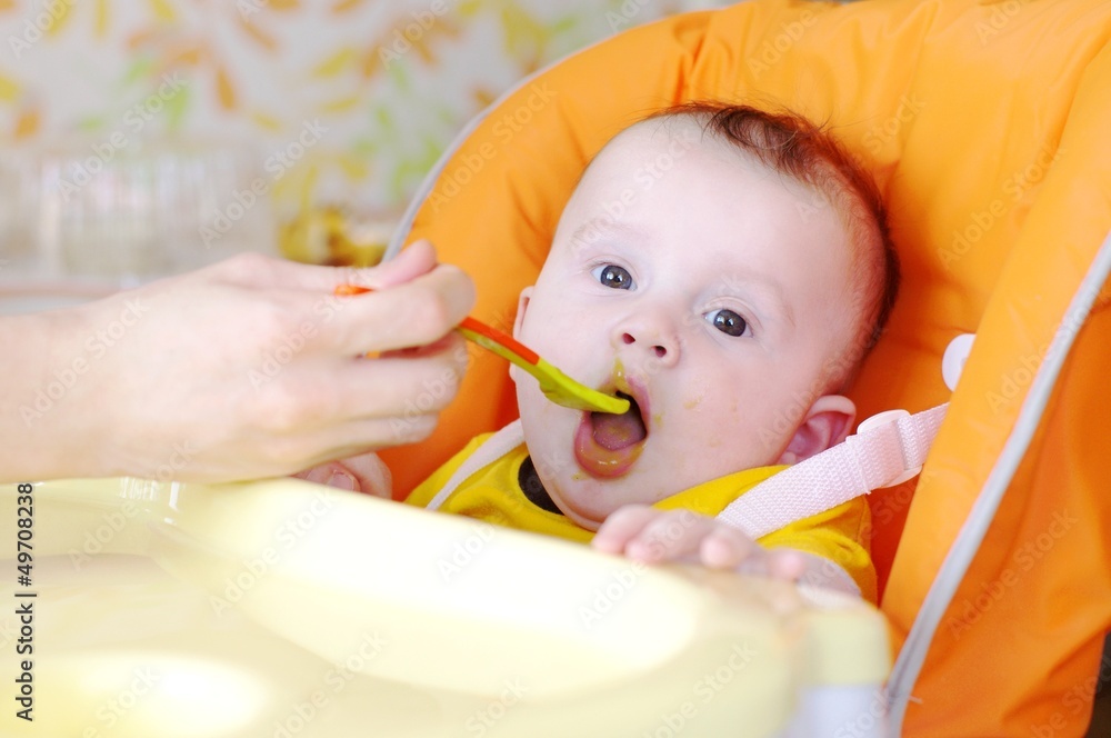 The five-months baby is fed by puree from a spoon The five-months baby is fed by puree from a spoon