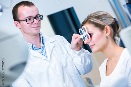 Optometry concept - pretty young woman having her eyes examined