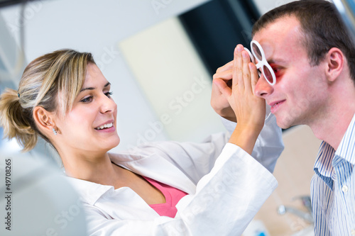 Optometry concept - handsome young man having his eyes examined