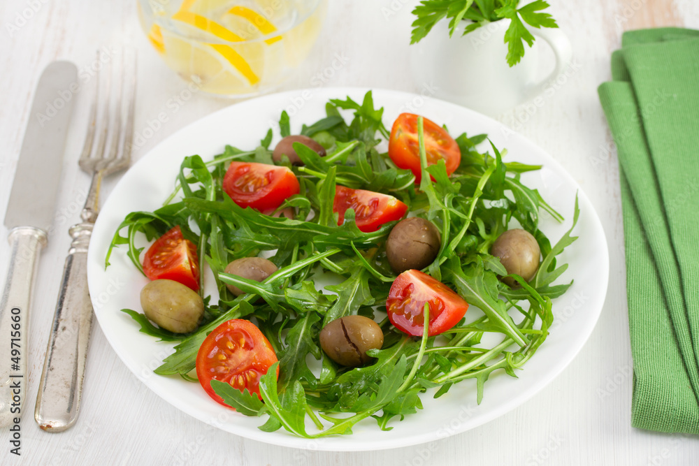 rucola with tomato and olives on the plate