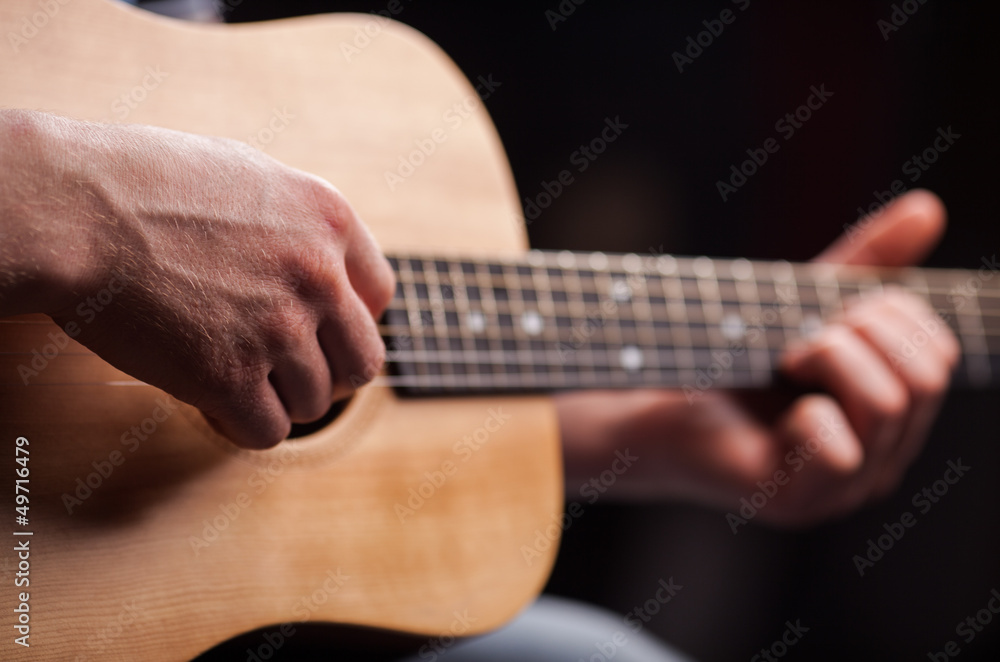 Fototapeta premium Brown guitar in hands in the guy playing it