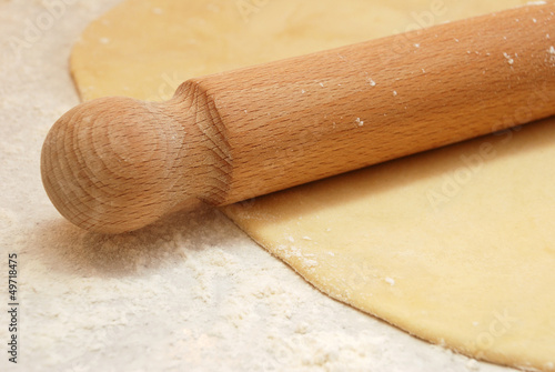 Detail of a wooden rolling pin on rolled out pastry