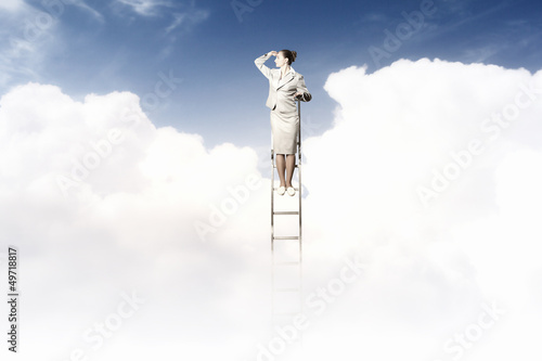 Businesswoman standing on ladder photo