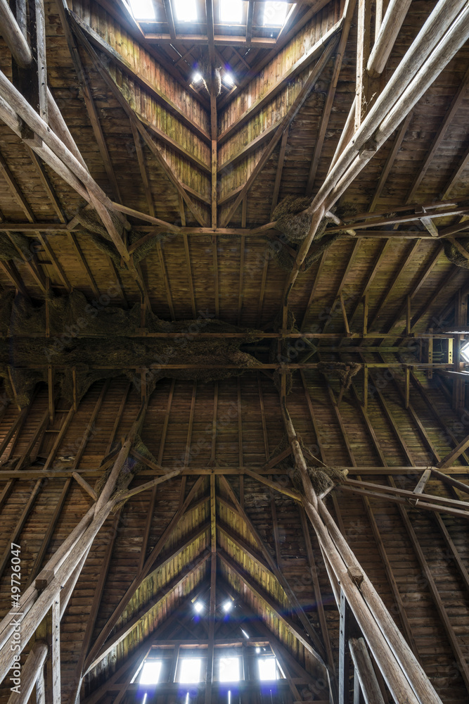 Old wooden barn roof with light shining through wooden boards