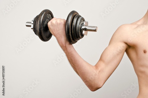 The before photo…. Arm of a slim young man lifting big weights.
