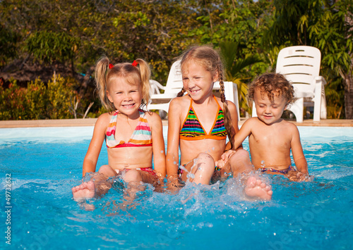 two little girls and little boy playing in the pool