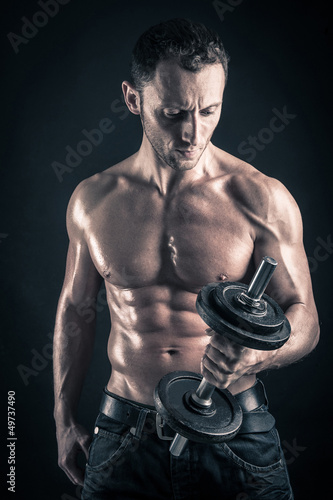 Confident young man shirtless portrait training with dumb-bell