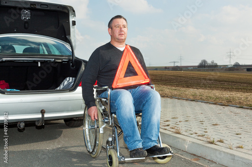 Man in a wheelchair and warning triangle next to his car © Edler von Rabenstein