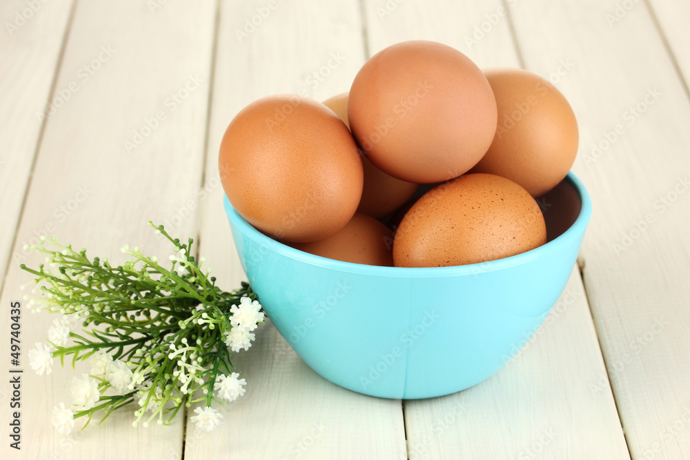 Eggs in blue bowl on wooden table close-up Eggs in blue bowl on wooden table close-up