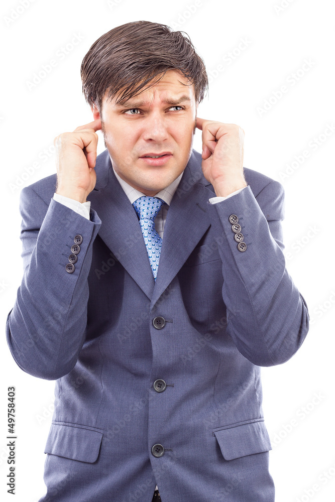 Young businessman with fingers in his ears protecting himself f Young businessman with fingers in his ears protecting himself f